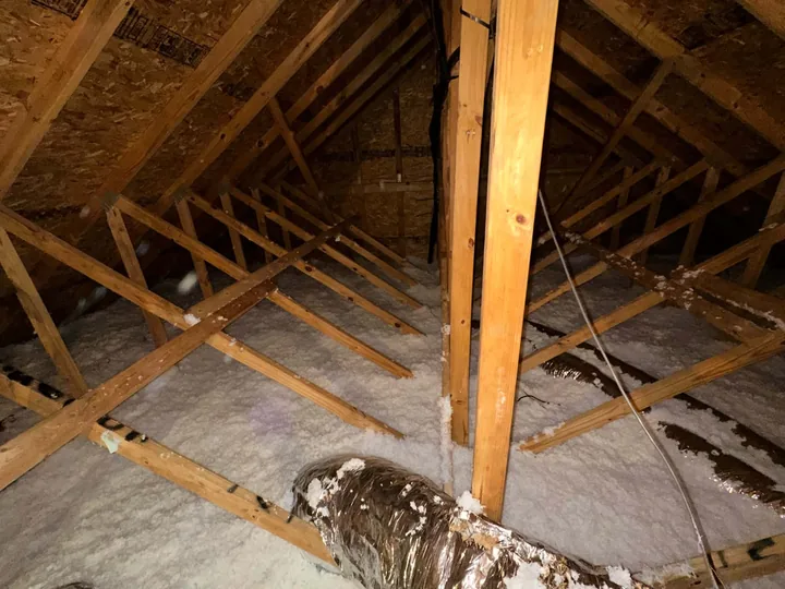 The ridge of a finished attic, clean insulation running the full length between the trusses.