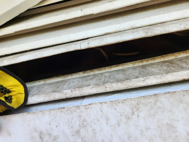 Close view of the gap behind the gable vent louvers with a work glove at the edge.