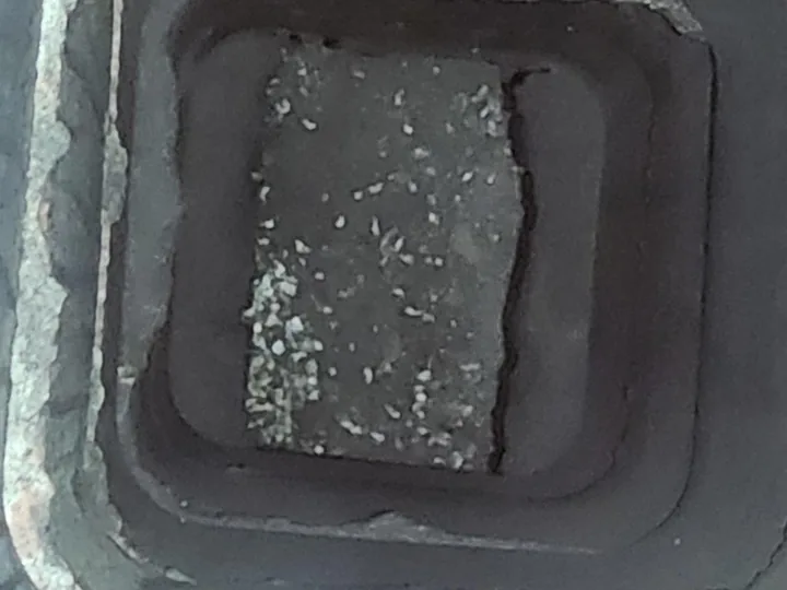 Looking down inside a chimney, the brick ledge and walls streaked with bird droppings.
