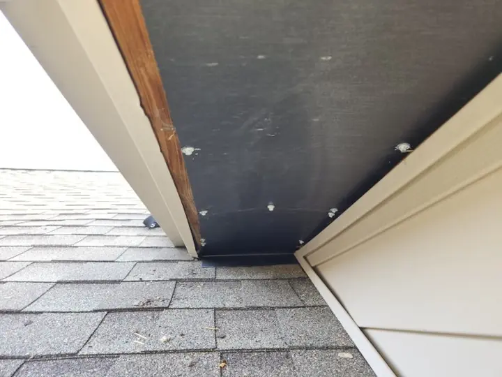 A soffit return opened up during repair, showing steel flashing being fitted behind the trim.