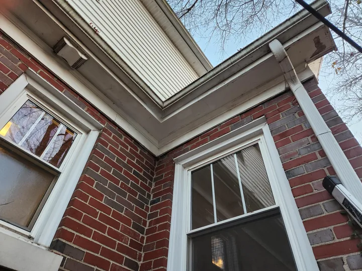 The cornice and gutter line of a brick house after repair, closed and painted.